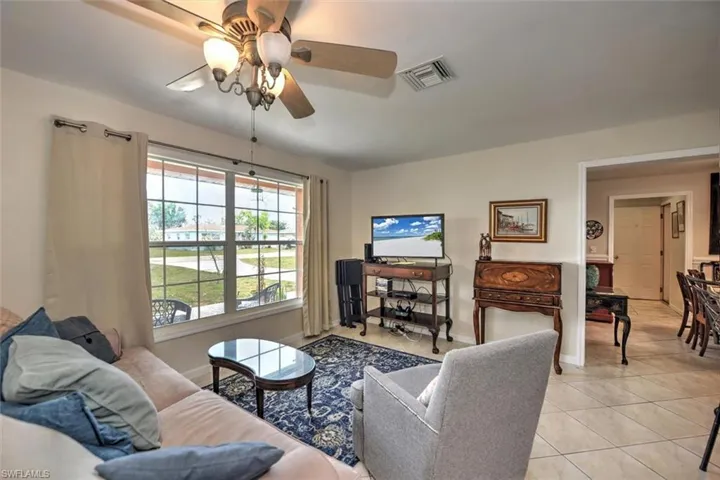 Living room with visible vents, a ceiling fan, baseboards, and light tile patterned floors