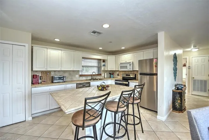 Kitchen featuring a kitchen breakfast bar, visible vents, a sink, light tile patterned floors, and stainless steel appliances