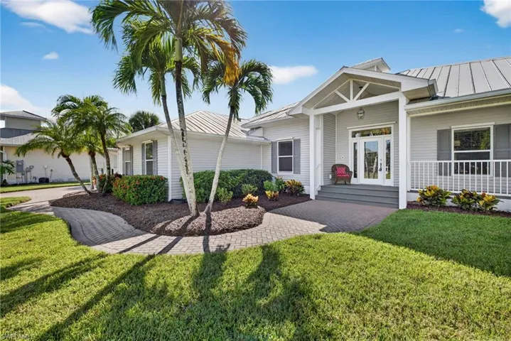 View of front of property featuring a standing seam roof, a metal roof, a porch, and a front lawn