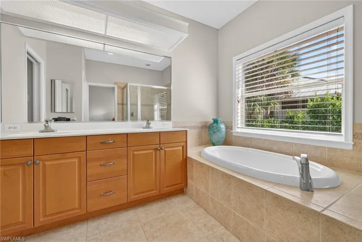 Full bathroom with double vanity, a garden tub, a shower stall, and light tile patterned floors