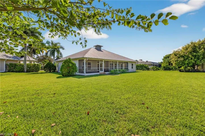 Back of house featuring a lawn, a sunroom, and a metal roof