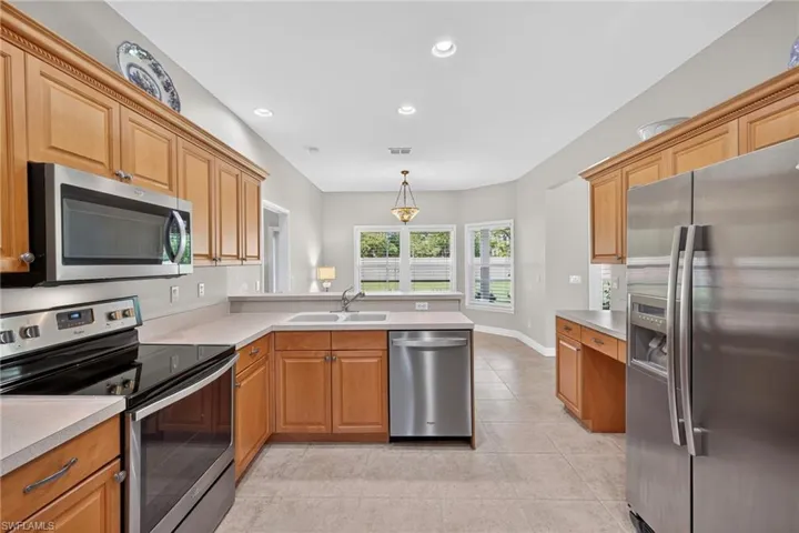 Kitchen featuring stainless steel appliances, recessed lighting, light countertops, light tile patterned floors, and hanging light fixtures