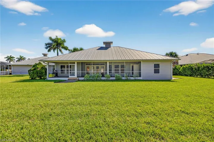 Rear view of house with a lawn, a sunroom, and a metal roof