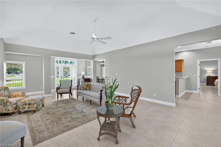 Living area featuring light tile patterned floors, ceiling fan, and a chandelier