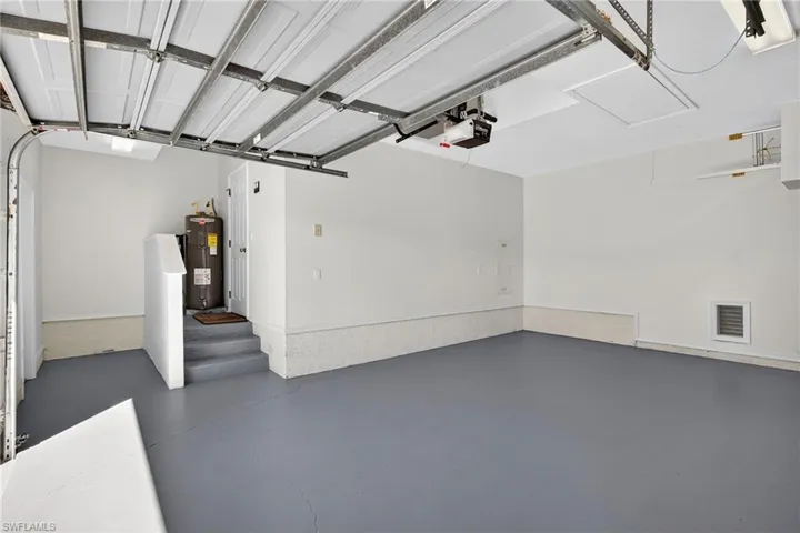 Garage featuring electric water heater and a garage door opener