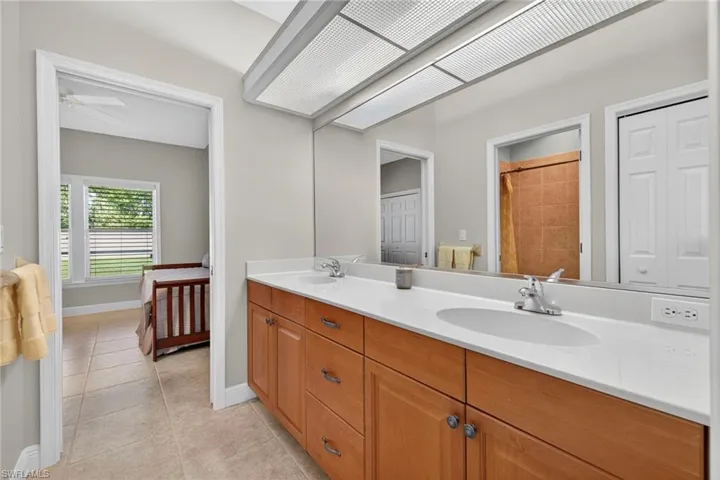 Ensuite bathroom featuring double vanity and light tile patterned floors