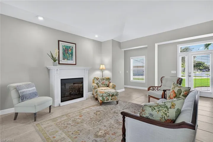 Living area with a glass covered fireplace, light tile patterned floors, and recessed lighting