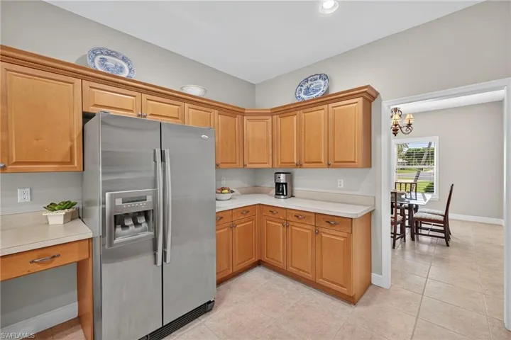 Kitchen featuring stainless steel fridge with ice dispenser, light countertops, light tile patterned flooring, a chandelier, and recessed lighting