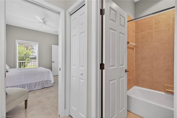 Bathroom with ensuite bathroom, tub / shower combination, light tile patterned flooring, and ceiling fan