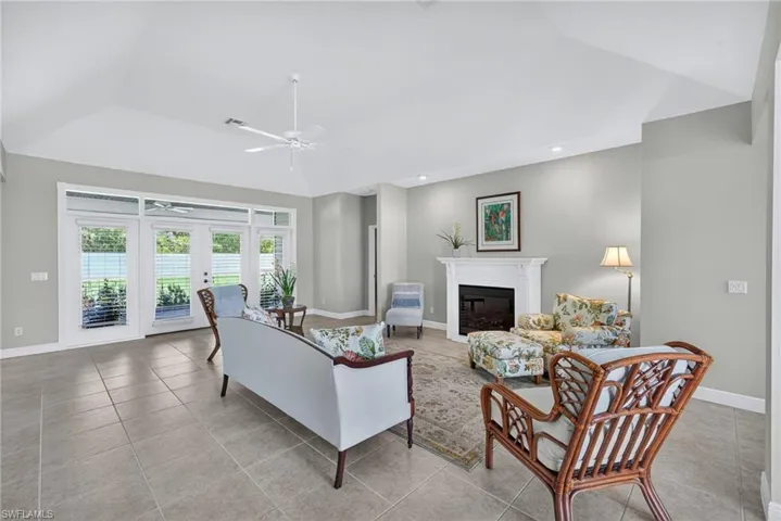 Living area with a glass covered fireplace, light tile patterned floors, recessed lighting, and ceiling fan