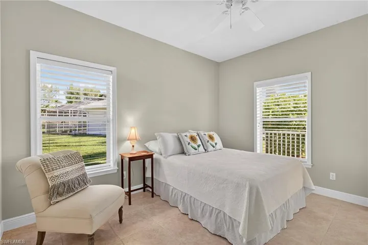 Bedroom with light tile patterned floors, multiple windows, and ceiling fan