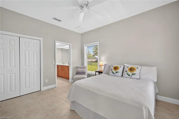 Bedroom featuring light tile patterned floors, a closet, ceiling fan, and ensuite bath