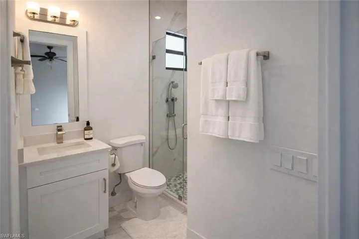 Full bathroom featuring vanity, a marble finish shower, and a ceiling fan