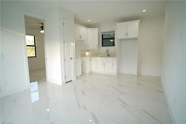 Kitchen featuring white cabinets, recessed lighting, light countertops, ceiling fan, and light marble finish floors