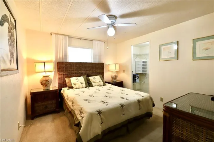 Bedroom with a spacious closet, a textured ceiling, carpet flooring, and ceiling fan