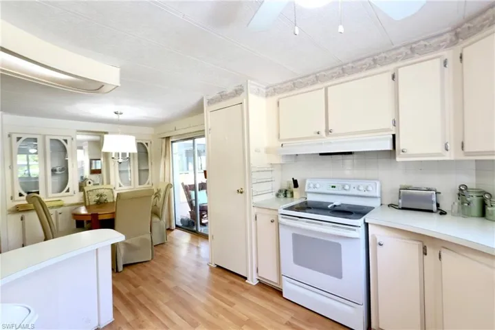 Kitchen featuring light hardwood / wood-style floors, decorative light fixtures, electric stove, tasteful backsplash, and ceiling fan