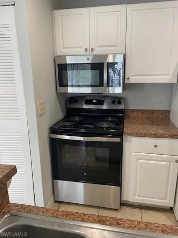 Kitchen with dark countertops, electric range, and white cabinets