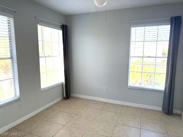 Empty room featuring a textured ceiling and light tile patterned floors