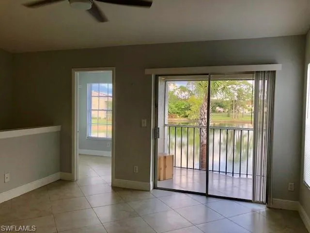 Unfurnished room with ceiling fan, a water view, and light tile patterned flooring