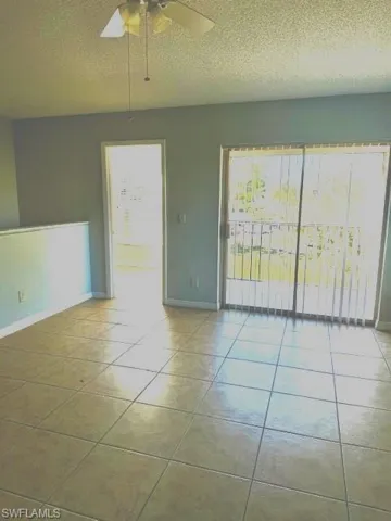 Unfurnished room featuring ceiling fan, light tile patterned floors, a textured ceiling, and plenty of natural light