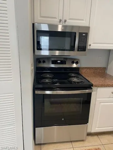 Kitchen view of white cabinets and stainless steel electric stove