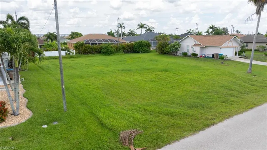 View of grassy yard featuring driveway and a residential view