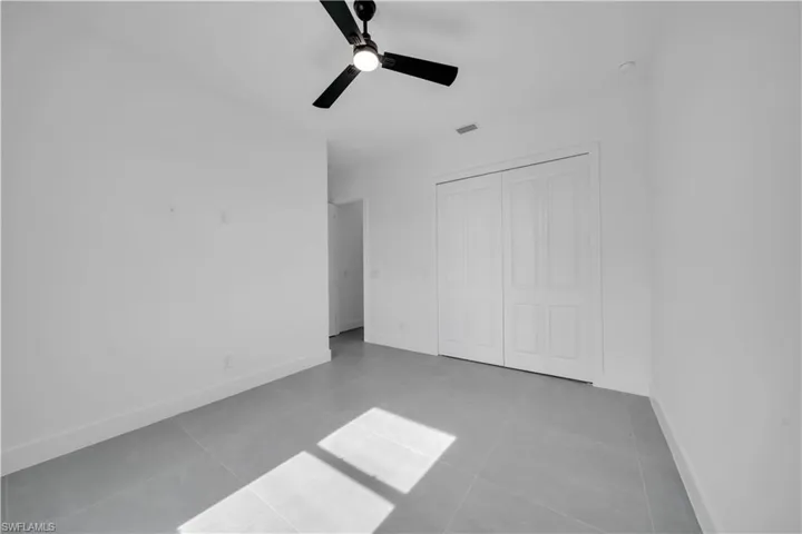 Unfurnished bedroom with a closet, a ceiling fan, and tile patterned floors