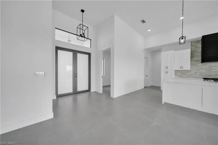 Kitchen with white cabinets, a high ceiling, light countertops, decorative light fixtures, and backsplash
