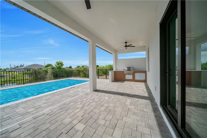 View of pool with exterior kitchen, ceiling fan, a fenced backyard, and a patio