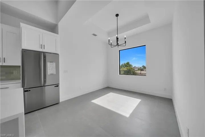 Unfurnished dining area with a raised ceiling and a chandelier