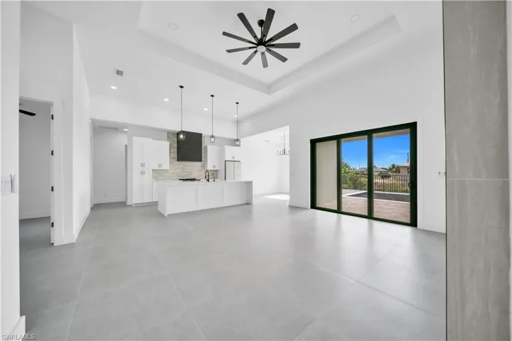 Unfurnished living room featuring a ceiling fan, recessed lighting, a towering ceiling, and a tray ceiling