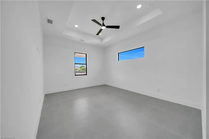 Unfurnished room featuring a raised ceiling, recessed lighting, and a ceiling fan