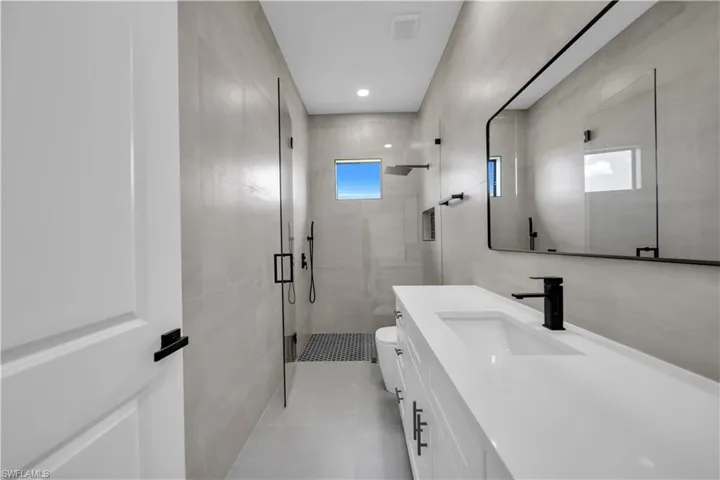 Full bathroom with a stall shower, vanity, tile walls, and recessed lighting