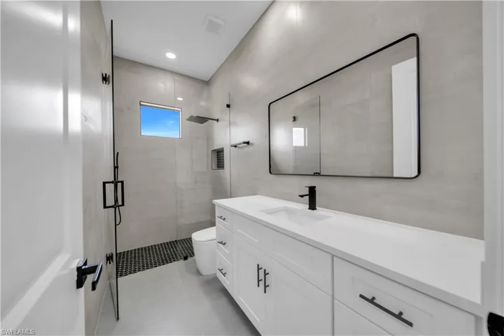 Full bath with a shower stall, vanity, tile walls, and tile patterned floors
