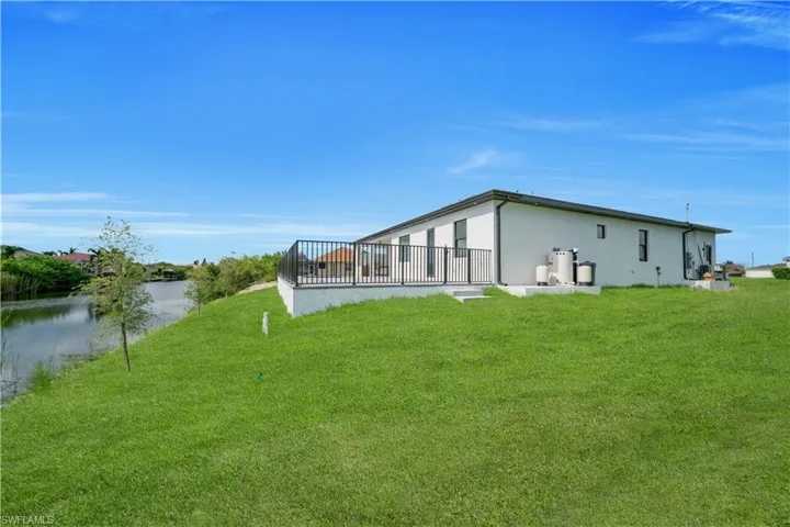 Rear view of house with a yard, stucco siding, and a water view
