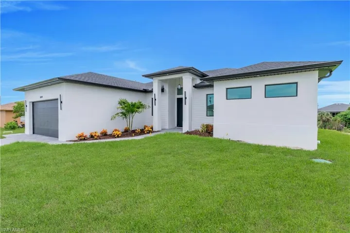 Prairie-style home featuring a garage, a front lawn, stucco siding, roof with shingles, and driveway