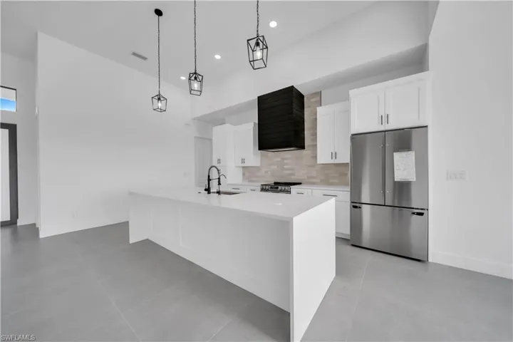 Kitchen with appliances with stainless steel finishes, light countertops, extractor fan, white cabinetry, and recessed lighting