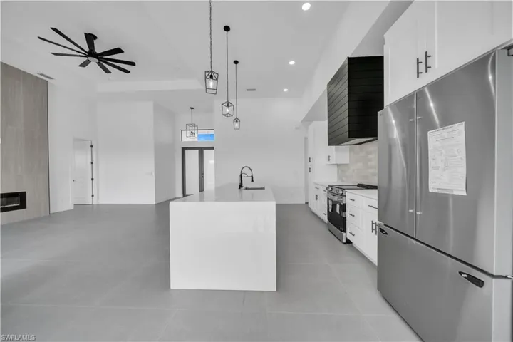 Kitchen with appliances with stainless steel finishes, ceiling fan, white cabinets, open floor plan, and recessed lighting