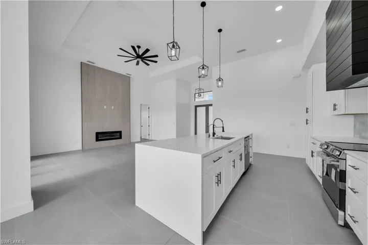 Kitchen with stainless steel electric range oven, a center island with sink, open floor plan, ceiling fan, and recessed lighting