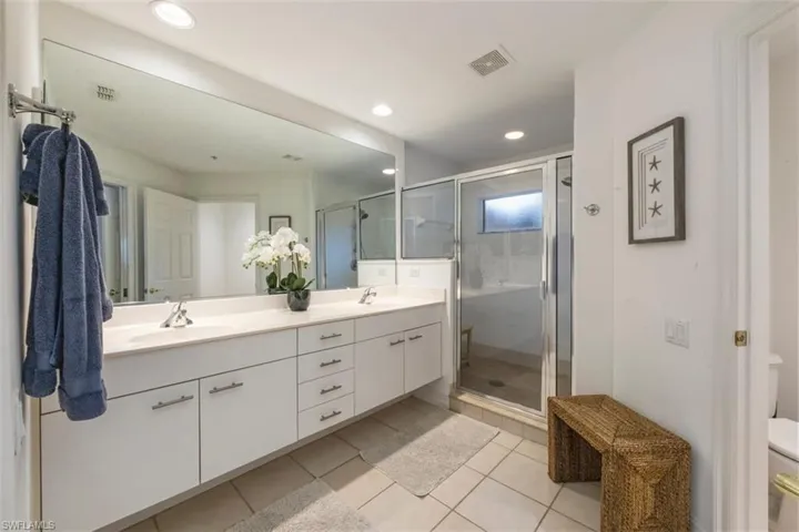 Light and open master bathroom with dual vanity, immaculately maintained.