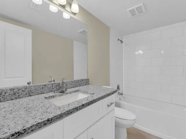 Bathroom featuring vanity, toilet, visible vents, and shower / bathtub combination