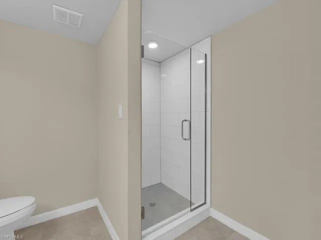 Full bathroom with baseboards, visible vents, a shower stall, tile patterned floors, and toilet