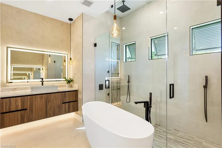 Experience an elegant oasis for relaxation and rejuvenation with floating custom vanities featuring under-cabinet LED lighting, dual vessel sinks, illuminated custom mirrors, designer lamps, and soft-closing cabinets