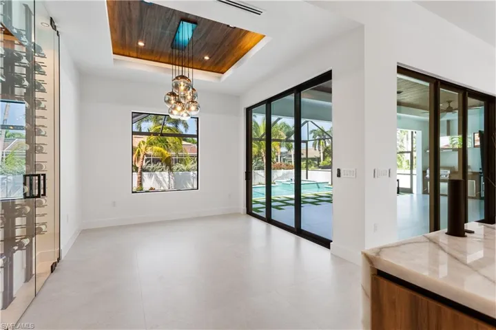ELEGANT DINING ROOM features FLAT WOODEN CELILING, DESIGNER'S LIGHTING, 9-ft TALL SLIDING DOORS to SCREENED LANAI & LARGE PICTURE WINDOW overlooking HEATED SALTWATER POOL & SPA