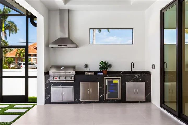 OUTDOOR KITCHEN is equipped w/ STAINELSS STEEL BULL 4-BURNER PROPANE GRILL, SIDE BURNER, MINI-REFRIGERATOR & COMMERCIAL SINK.