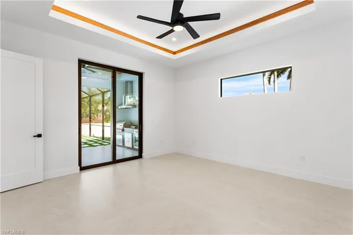 Retreat to this spacious master bedroom, featuring smooth walls, private sliding doors that lead to the screened lanai with a pool and spa, elegant wood doors and baseboards, recessed lighting, and a charming wooden ceiling accent!