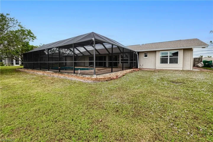 Rear of house with pool enclosure and yard