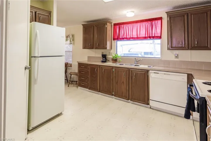 Kitchen with a textured ceiling, sink, and white appliances