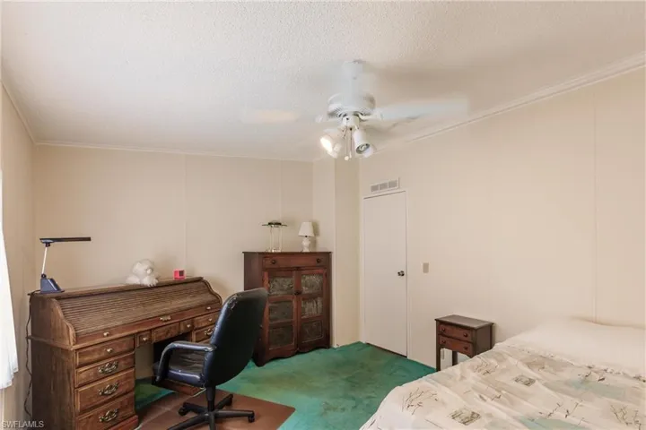 Bedroom with dark carpet, crown molding, a textured ceiling, and ceiling fan