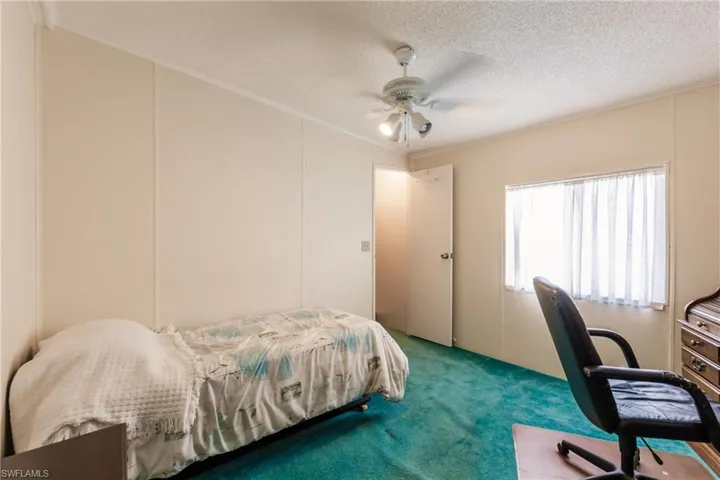Bedroom with ornamental molding, a textured ceiling, carpet, and ceiling fan